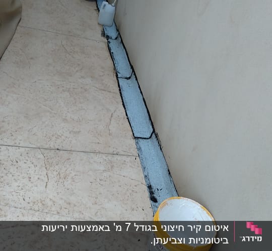 דלי צבע ומברשת ליד קיר אטום בחומר איטום